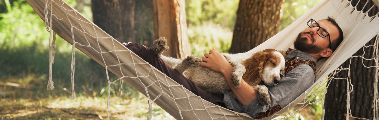 A man and his dog relax in a hammock