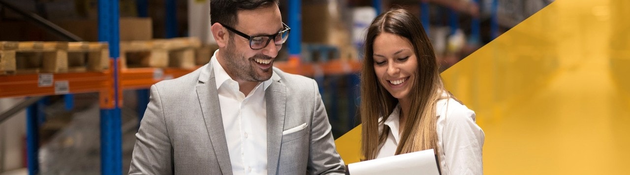 Female banker and male business owner smiling and conversing in warehouse