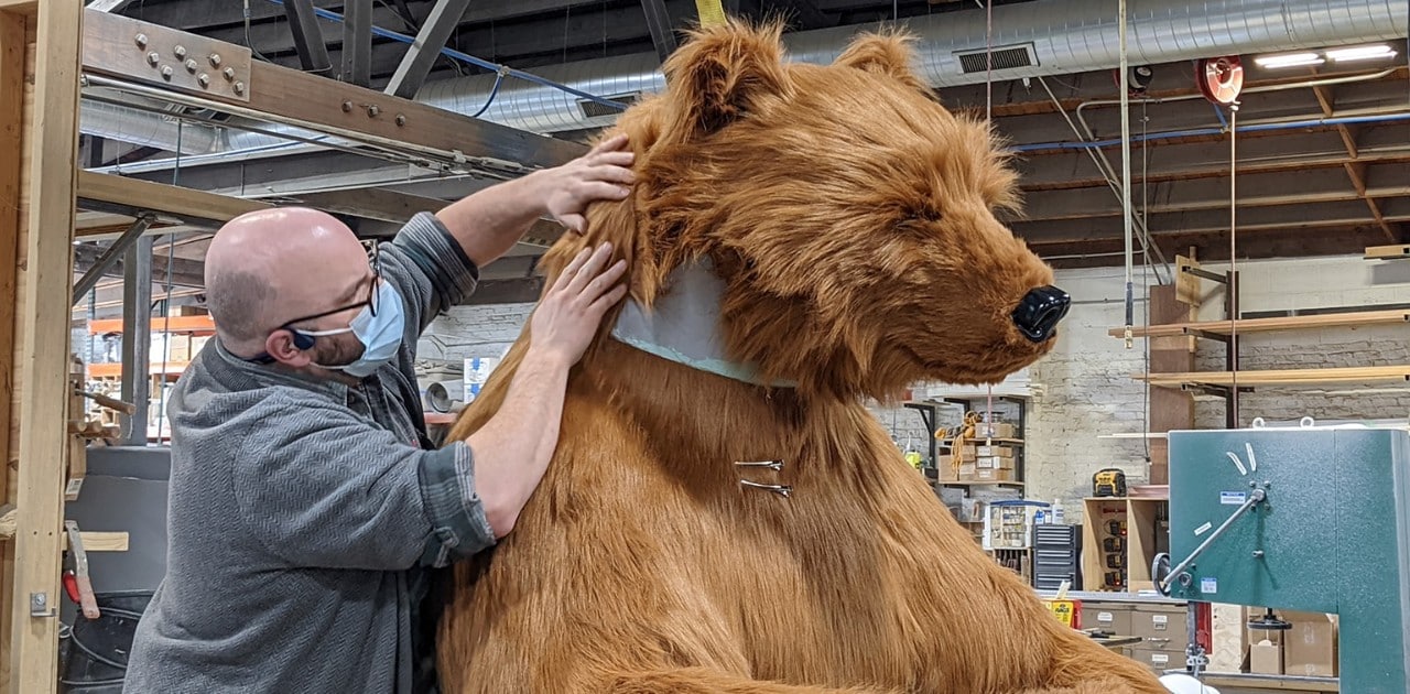 A man works on a life-size bear art piece