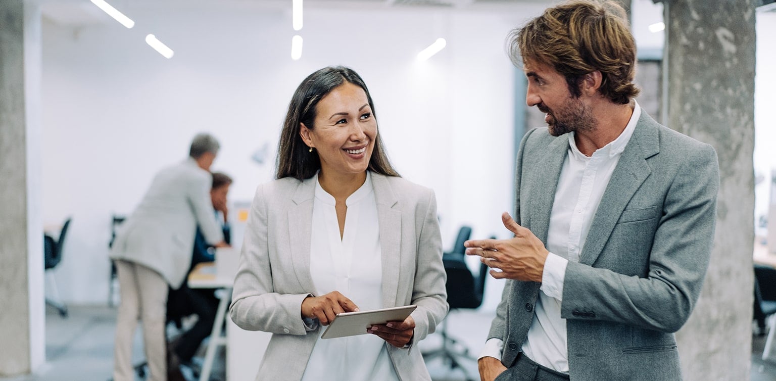 Female and male colleagues conversing outside conference room