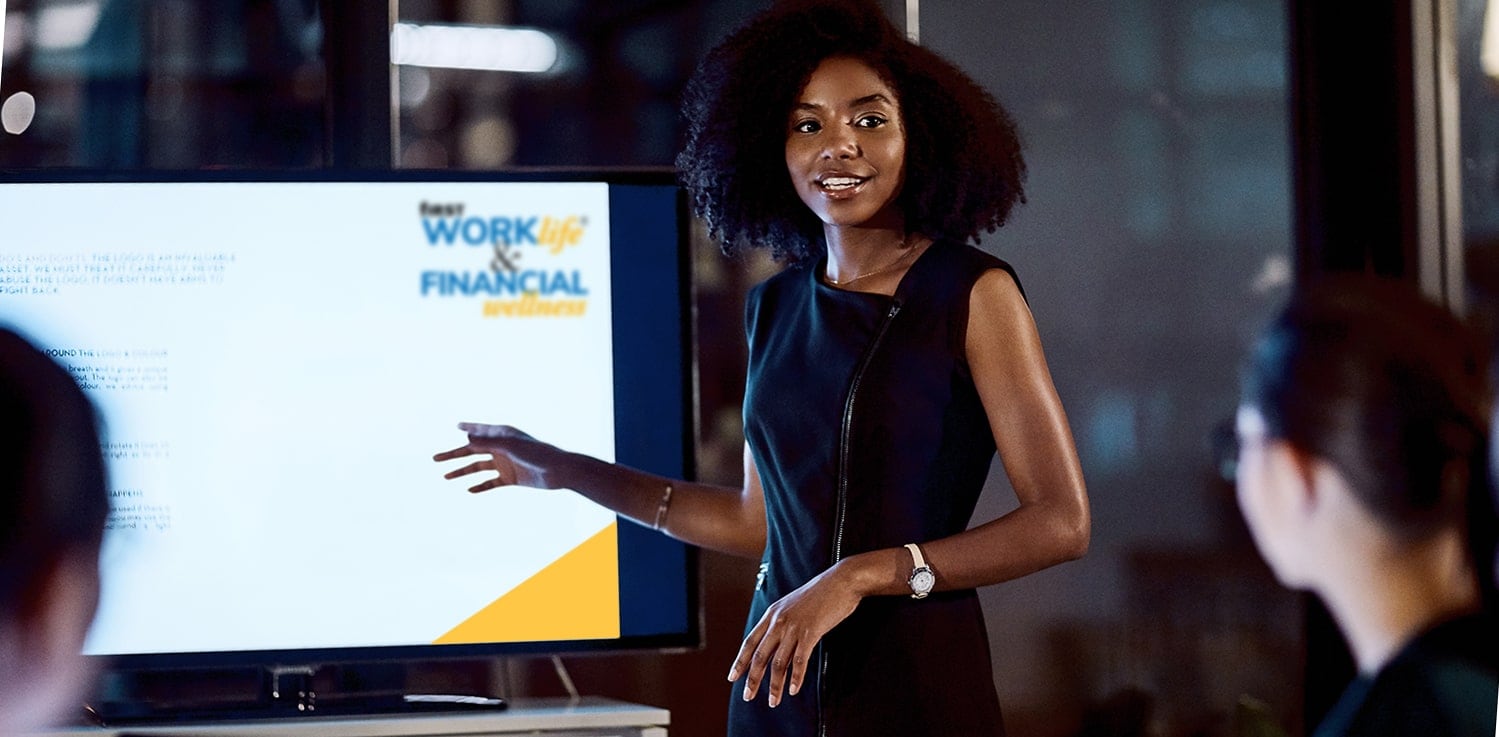 Female banker presenting in front of video screen with First WORKlife® and Financial Wellness logo