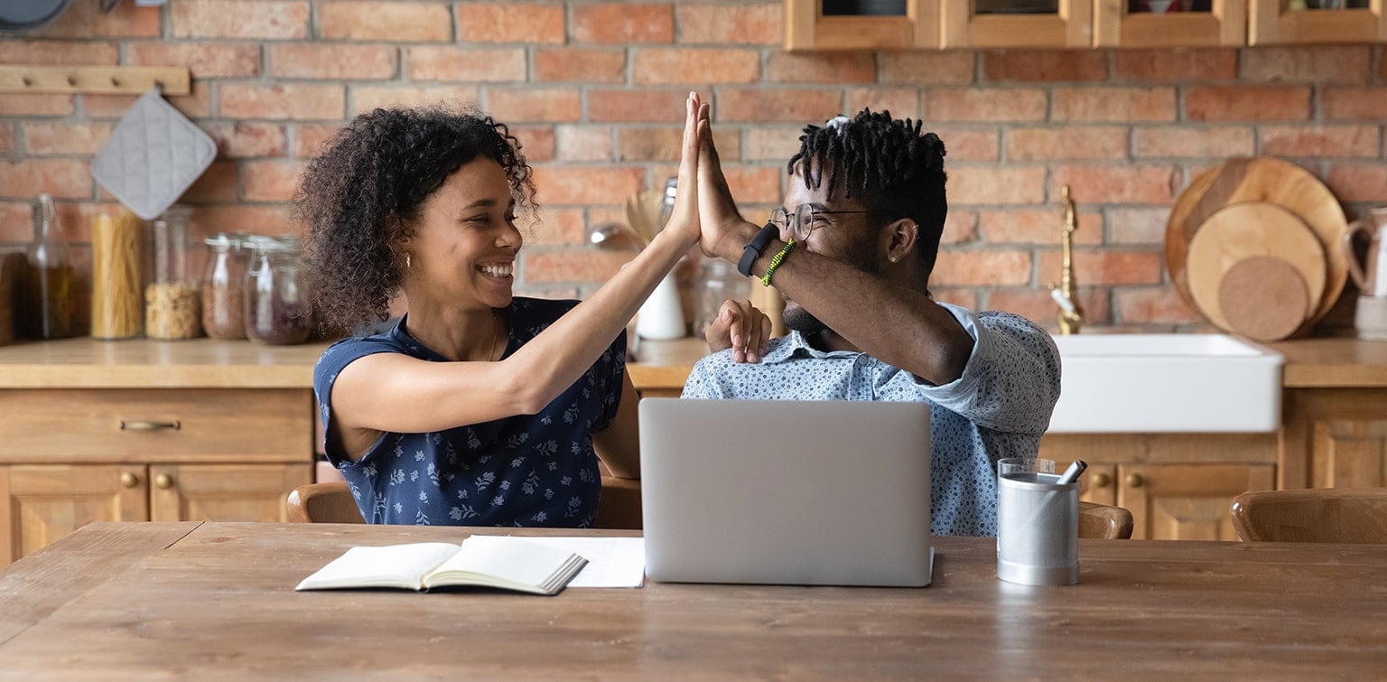 African American couple high fiving at desk. 