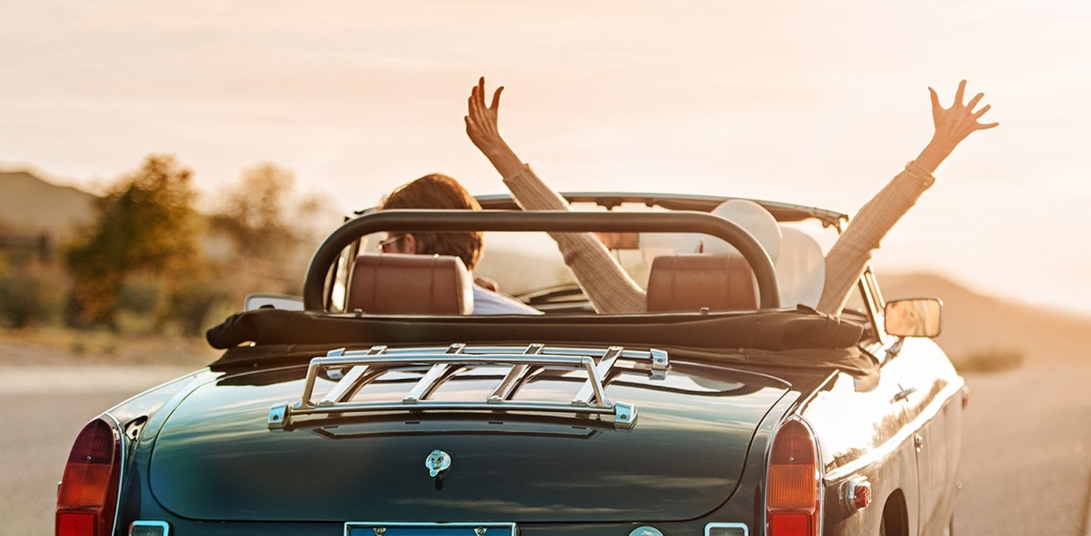 Young couple driving classic convertible on highway