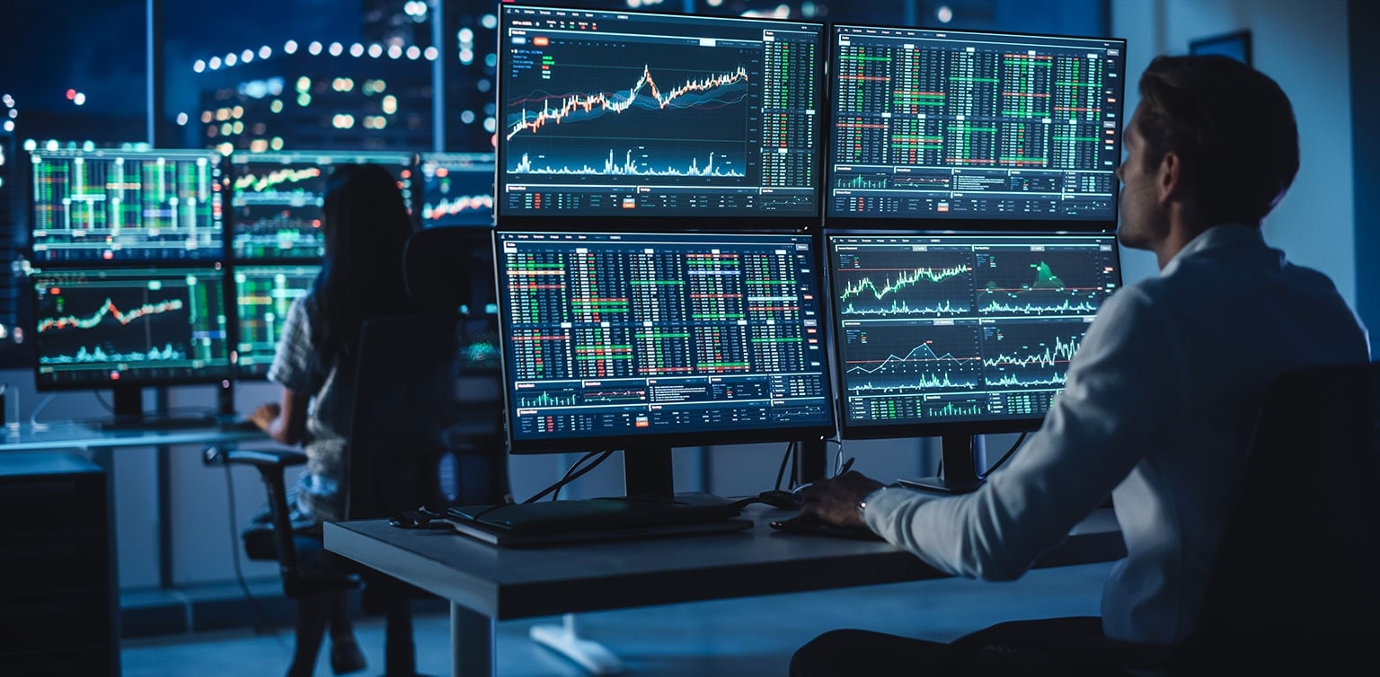 Financial analysts reviewing stock data on multiple monitors