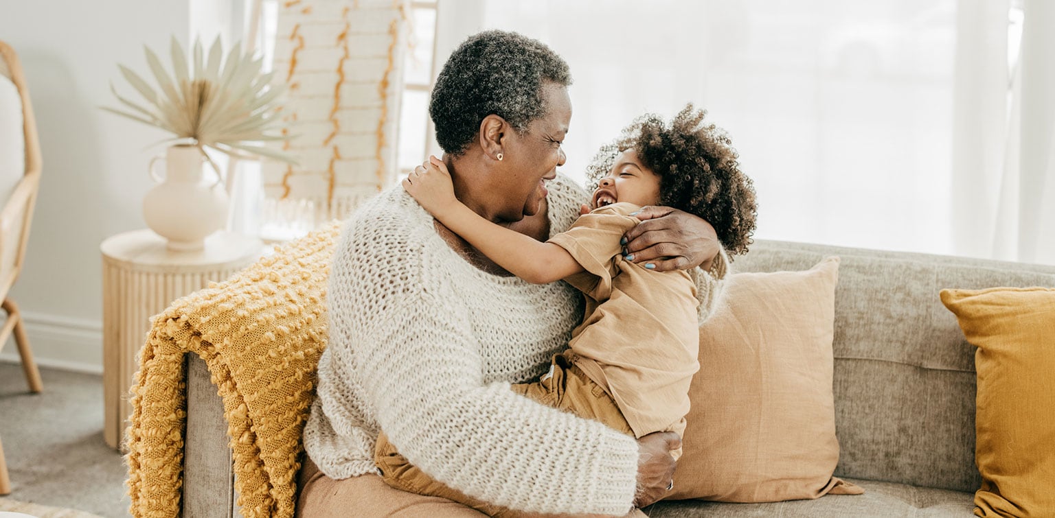 African-American grandmother hugging her granddaughter on a sofa