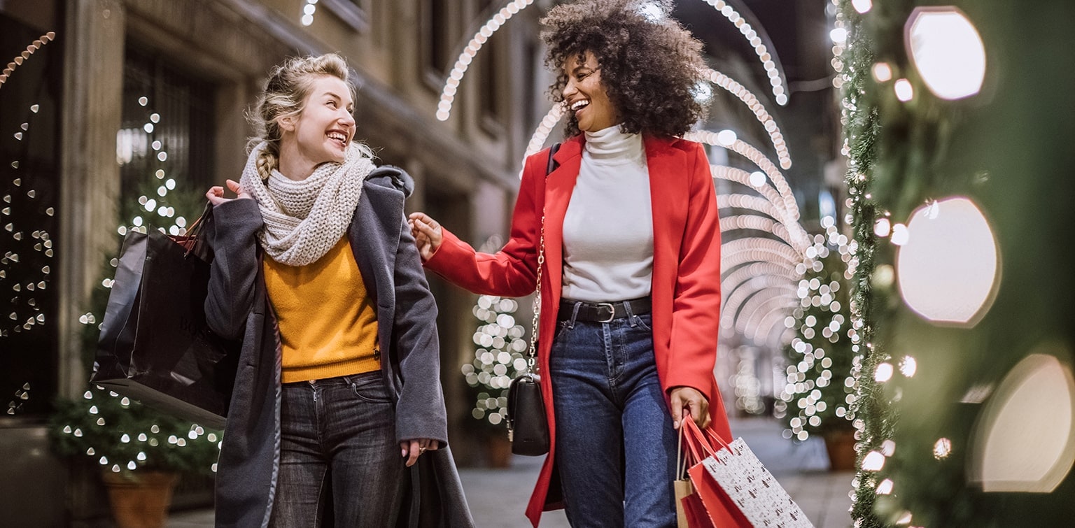 Happy Caucasian and African-American women shopping during the holidays