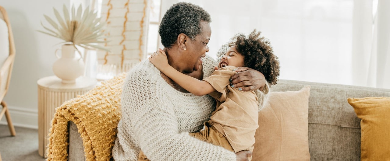 African-American grandmother hugging her granddaughter on a sofa