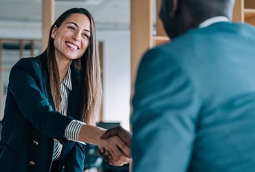 Female business succession specialist shaking hands with African-American business owner