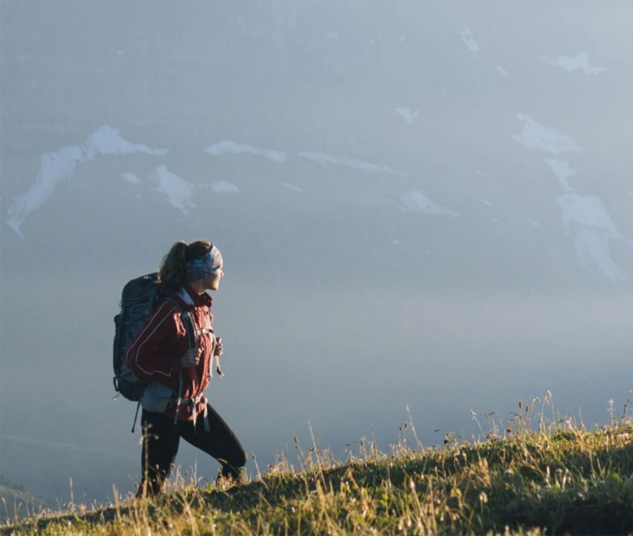 Woman hiking in a meadow with mountains in the background